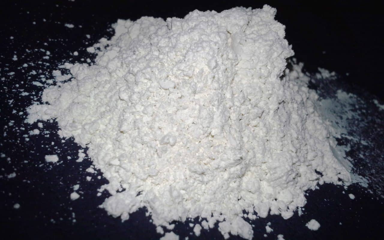 A loose pile of fine white diatomaceous earth powder on a dark surface