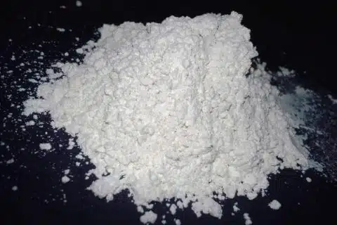 A loose pile of fine white diatomaceous earth powder on a dark surface