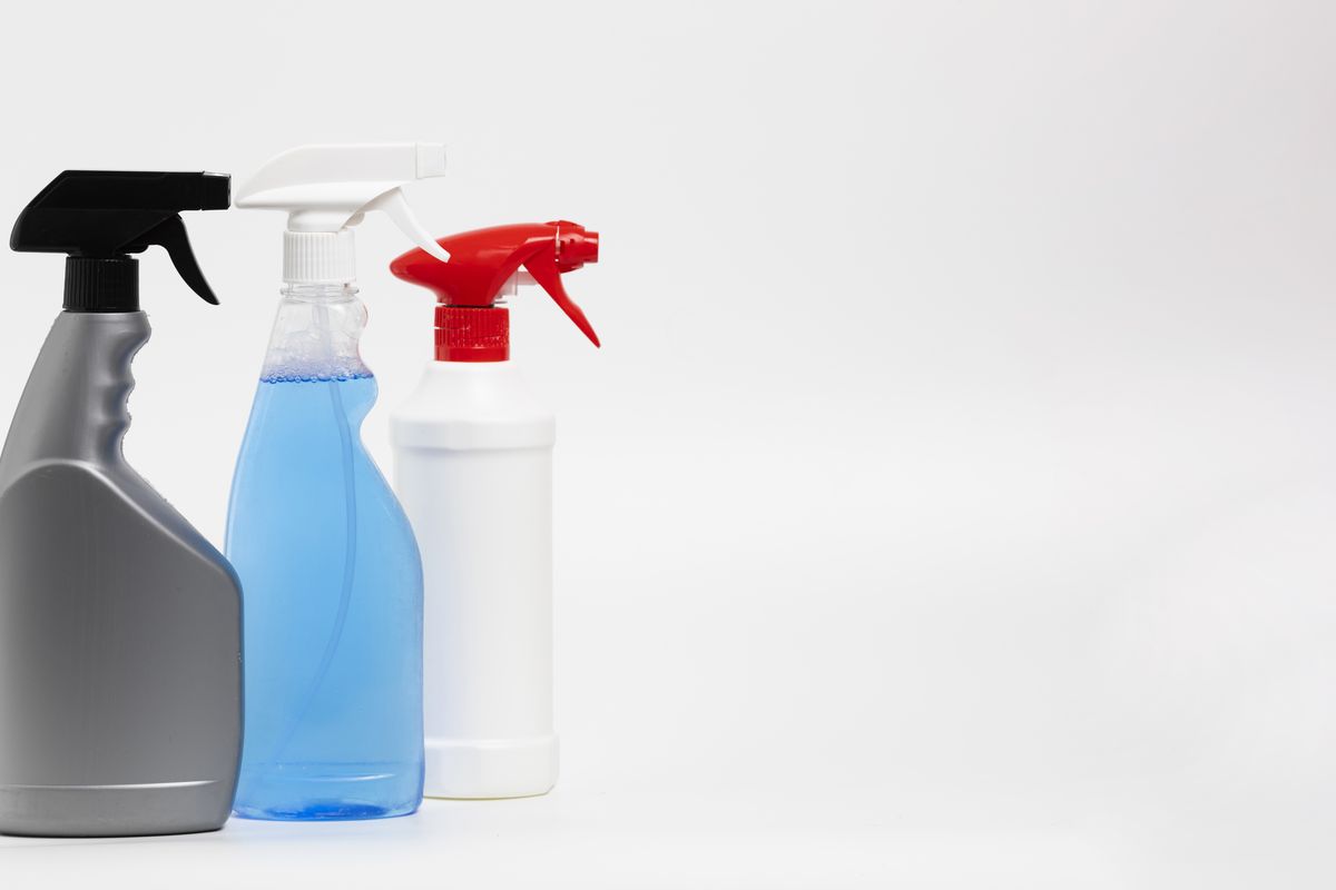 Household spray bottles of different sizes and nozzle types lined up on a surface