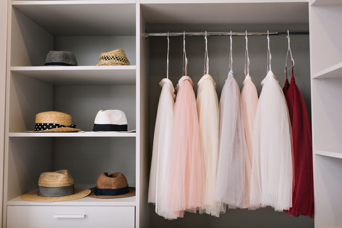 Bright wardrobe interior with garments hanging on a rail above open shelving