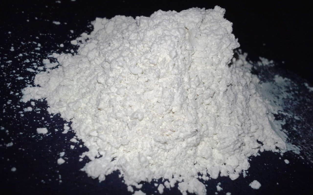 Fine off-white diatomaceous earth powder dusted in a thin line along a baseboard edge