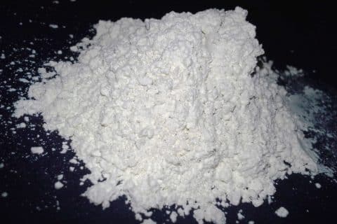 Fine off-white diatomaceous earth powder dusted in a thin line along a baseboard edge