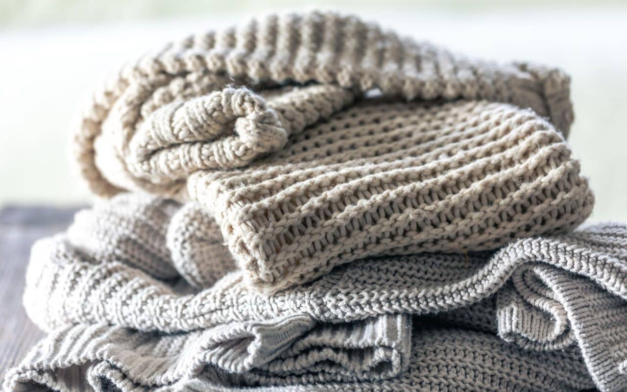 Stack of folded knitted wool sweaters on a wooden surface