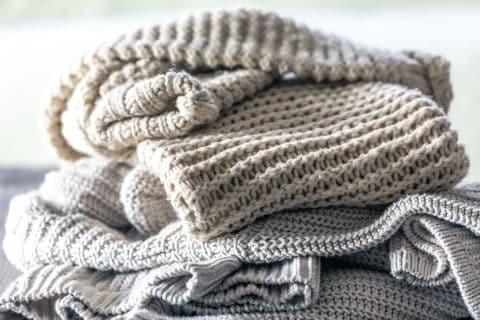 Stack of folded knitted wool sweaters on a wooden surface