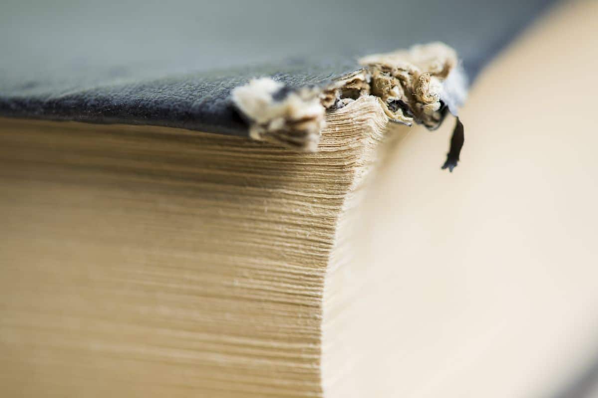 Old hardback book with a worn, damaged cover and frayed binding