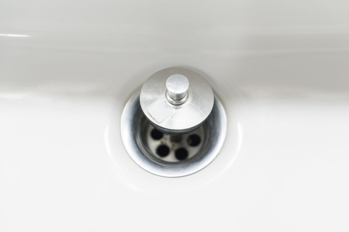 Close-up of an open drain hole in a white washbasin
