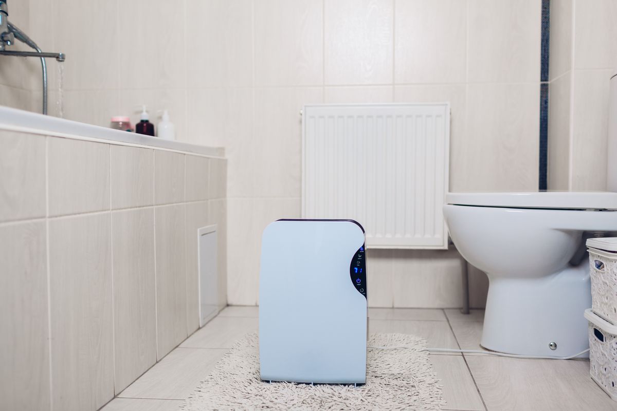 Portable dehumidifier with a humidity readout running on a bathroom floor