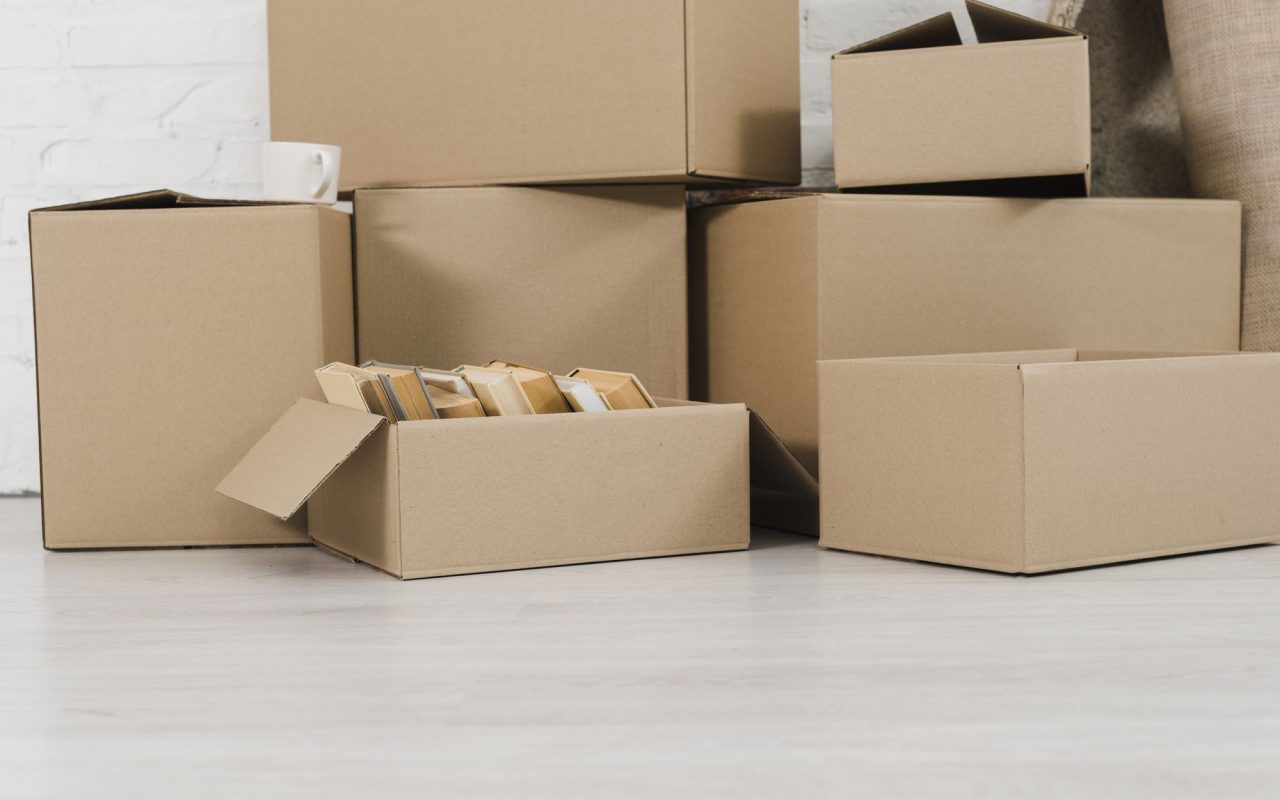 Cardboard moving boxes stacked in a pile directly on a bare floor