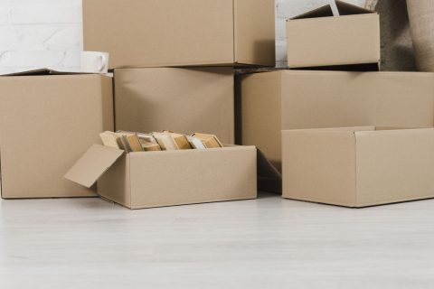 Cardboard moving boxes stacked in a pile directly on a bare floor
