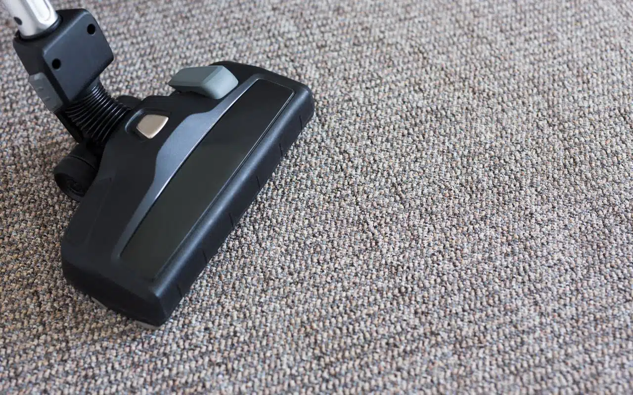 Close-up of a vacuum cleaner head being pushed across a household carpet