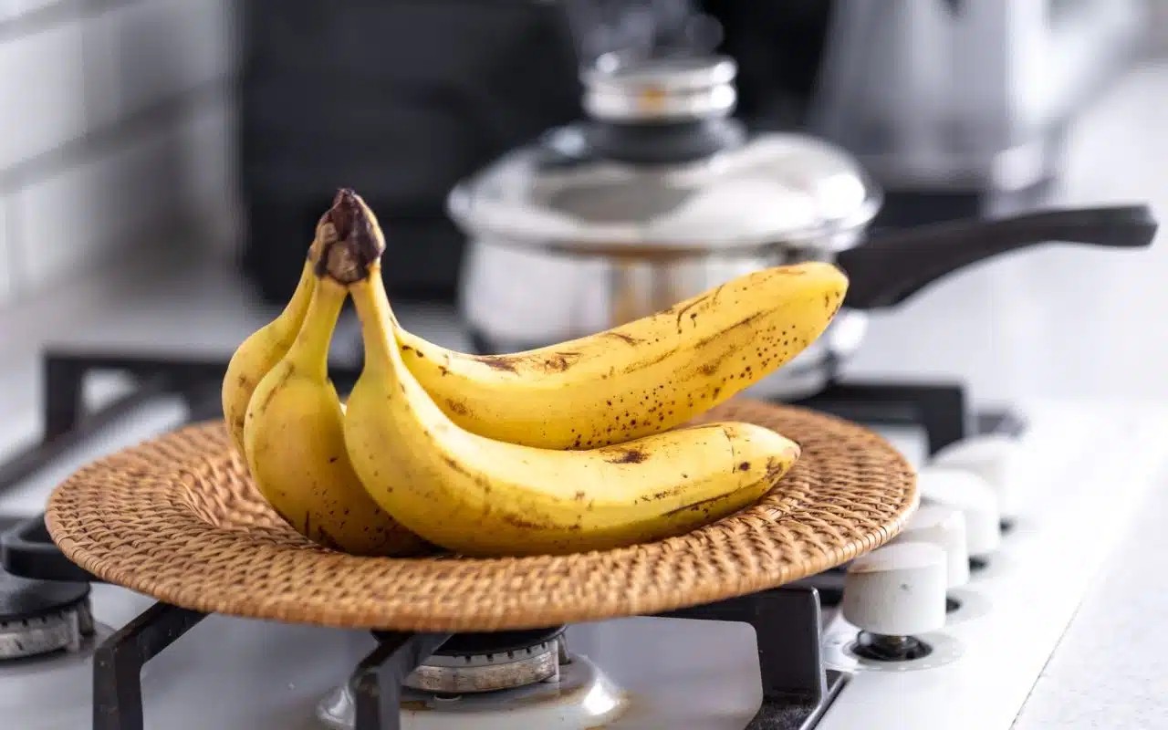 Bunch of ripe bananas sitting on a counter in a bright kitchen
