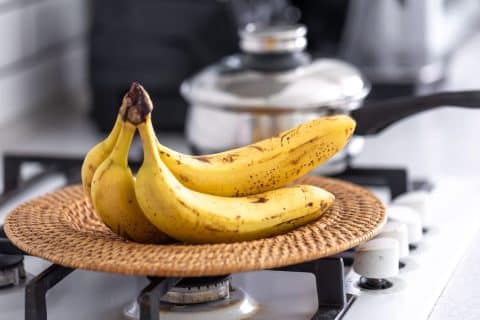 Bunch of ripe bananas sitting on a counter in a bright kitchen