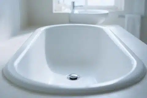 Empty white enamel bathtub seen from one end, smooth sides sloping to the drain